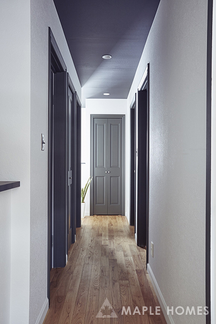 黒く塗装された無垢材のドアと白い壁のコントラストが美しい廊下